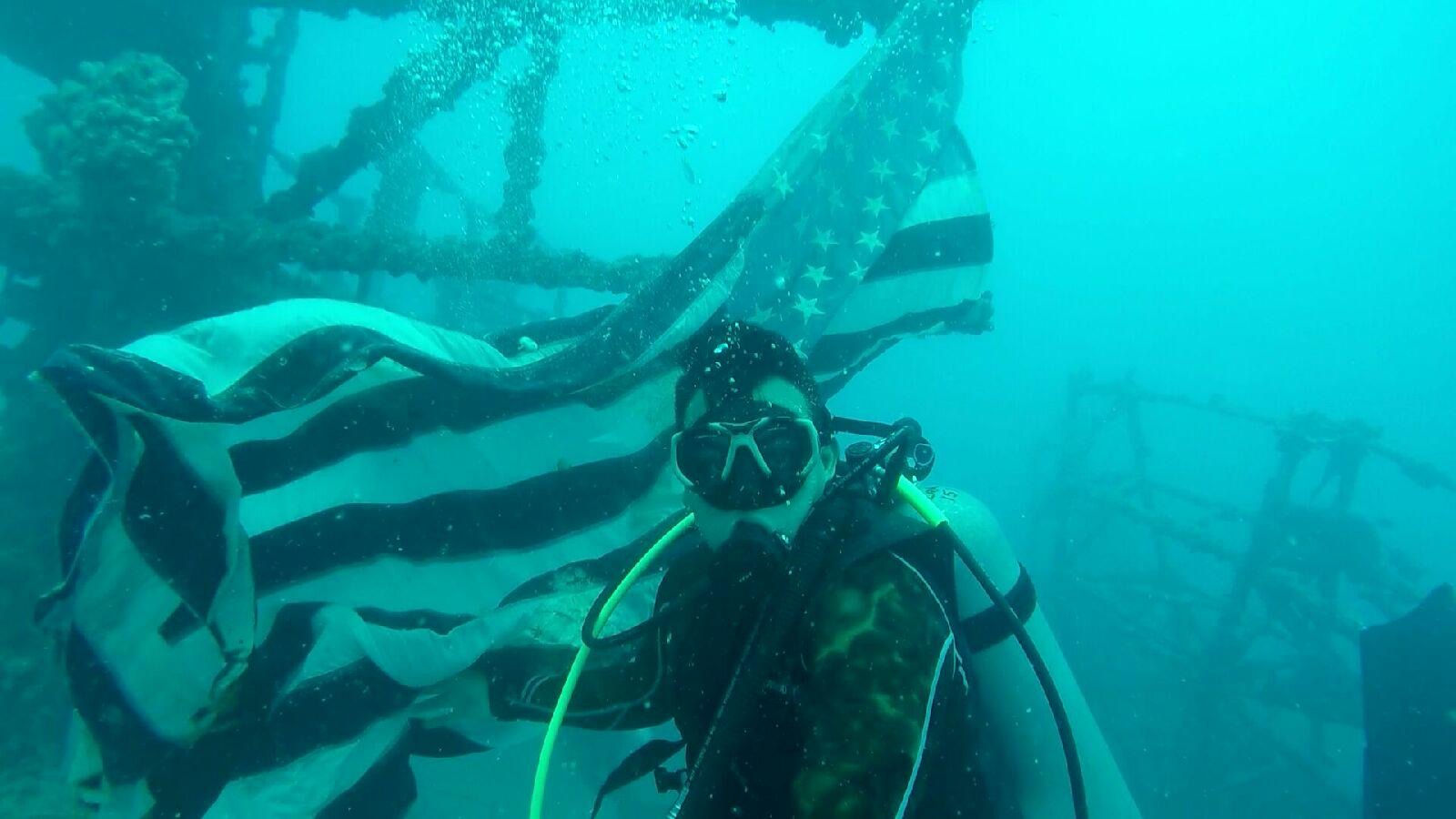 Richard Bargas scuba diving a wreck with the American flag